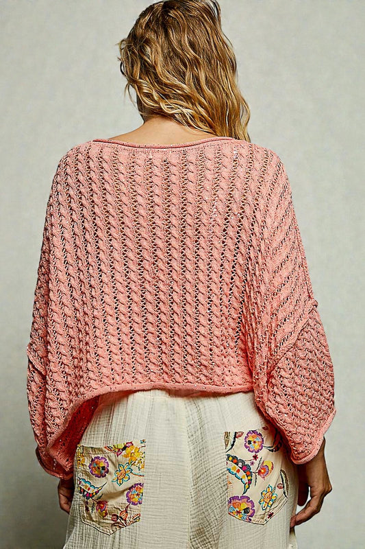 Person wearing a pink knitted sweater with a neutral background