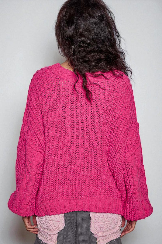 Person wearing a pink knitted sweater against a plain background