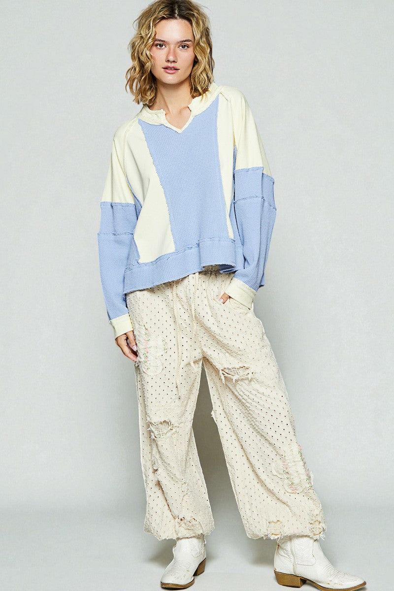 Person wearing a colorful sweater and patterned pants on a plain background