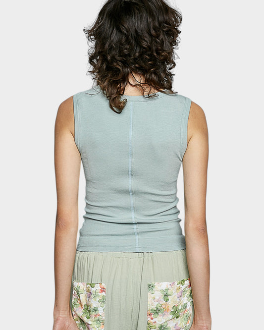 Woman wearing a light green sleeveless top with floral skirt on a white background
