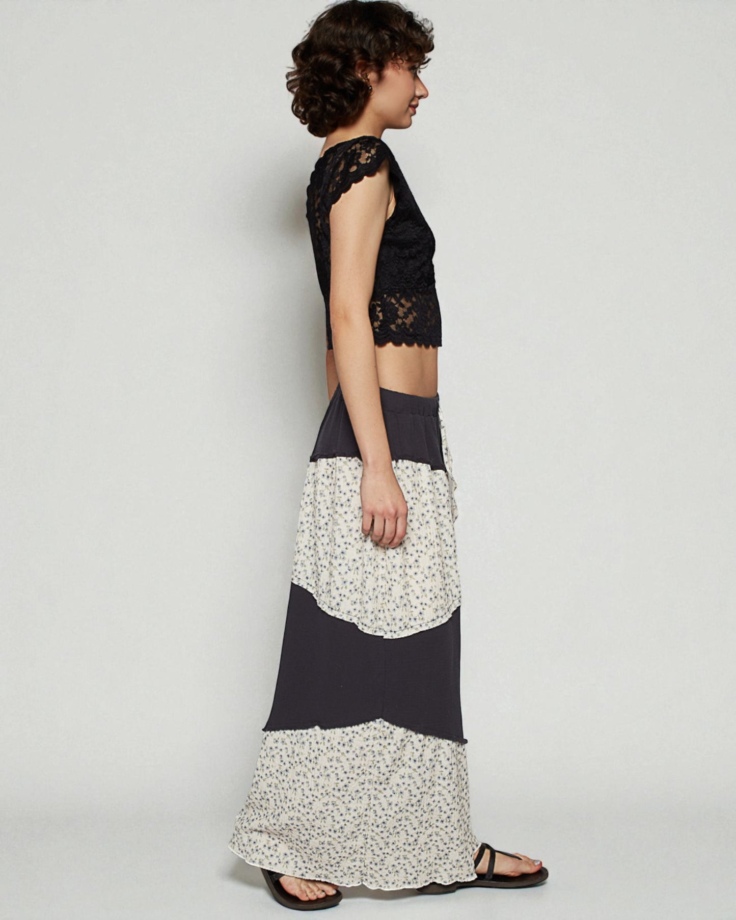Woman wearing a black lace top and a long floral skirt on a white background