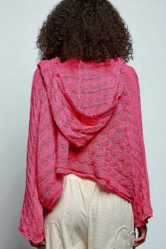 Person wearing a bright pink knitted shawl over shoulders on a plain background