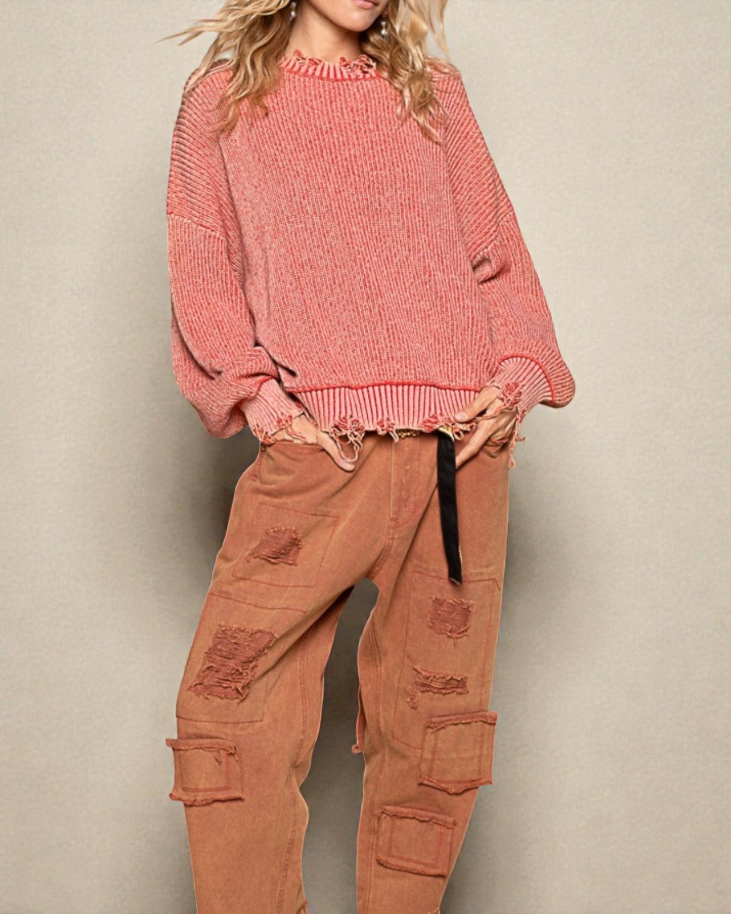 Person wearing a pink sweater and brown cargo pants against a beige background