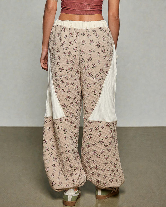Floral-patterned pants with white accents worn by a person on a neutral background