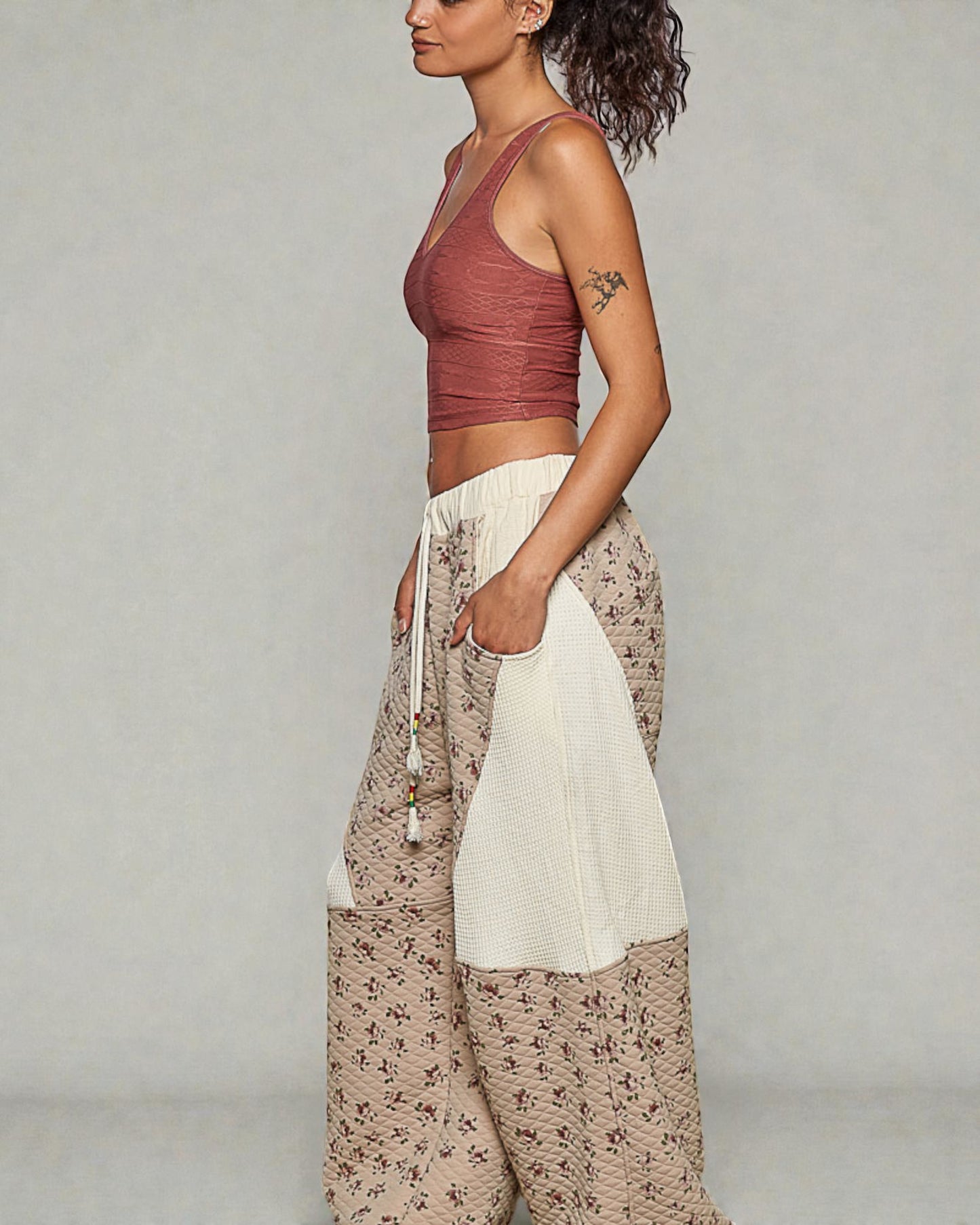 Woman wearing a rust-colored crop top and patterned pants on a plain background