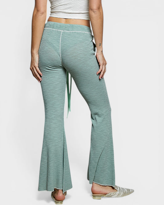 Green checkered flared pants worn by a person on a white background