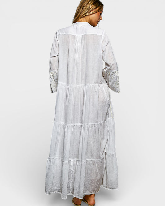 Woman wearing a long, light gray dress with lace details on a white background