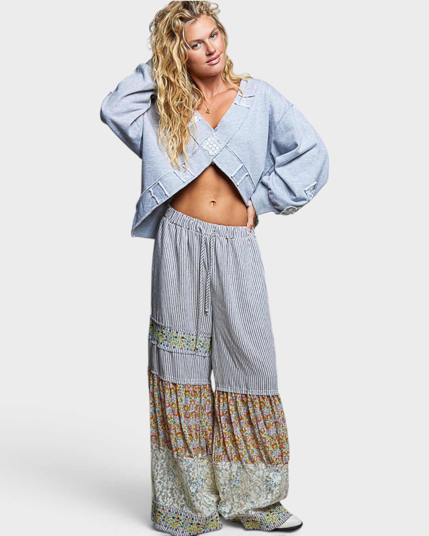 Woman wearing a light blue sweatshirt and patterned pants on a white background