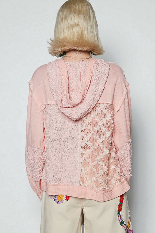 Person wearing a pink lace-trimmed top with a plain background