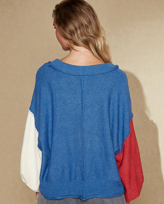 Person wearing a blue, white, and red color-blocked sweater against a beige background