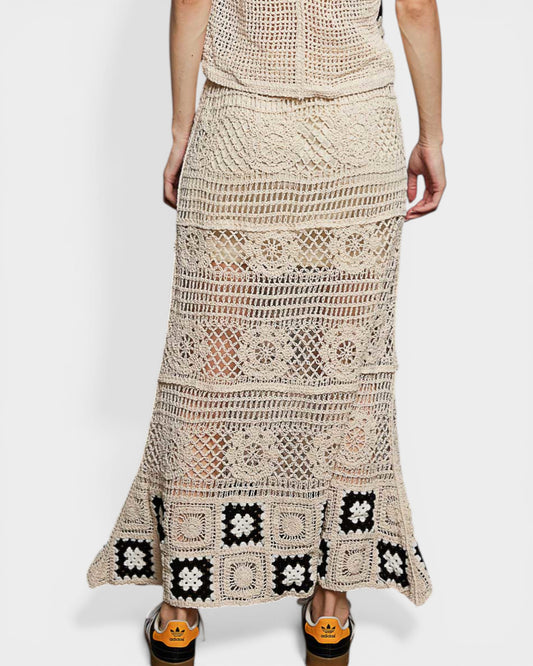 Beige crochet skirt with black square patterns worn by a person on a white background