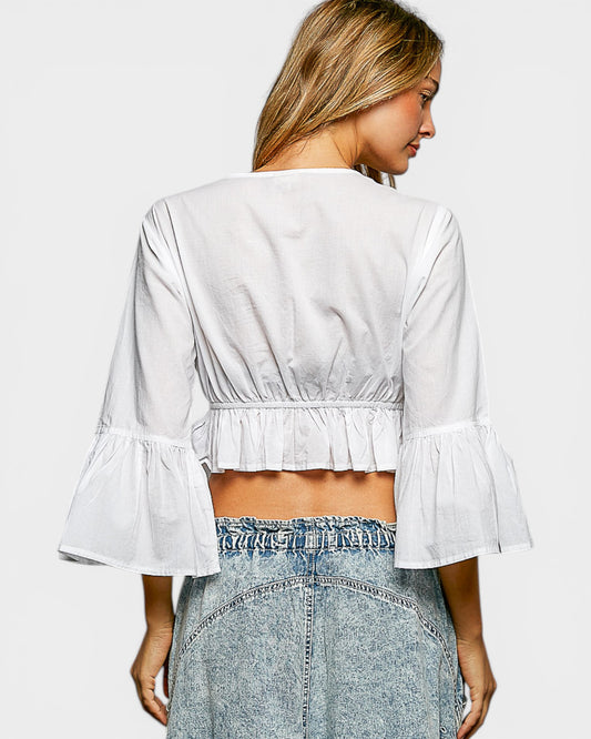 Woman wearing a white blouse with ruffled sleeves and a denim skirt on a light gray background