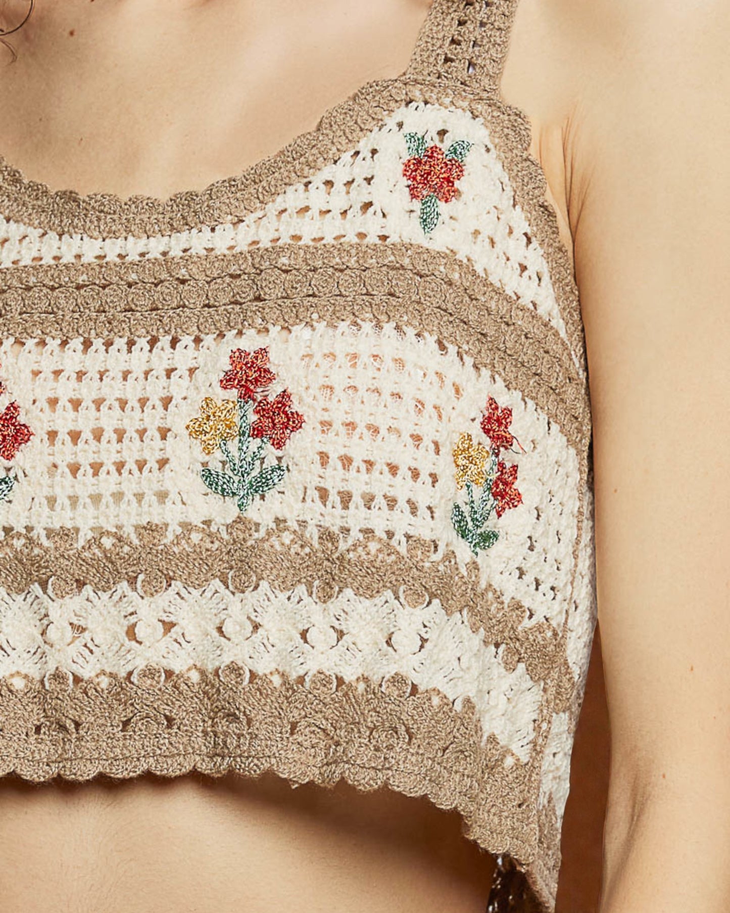 Close-up of a crochet top with floral patterns on a neutral background