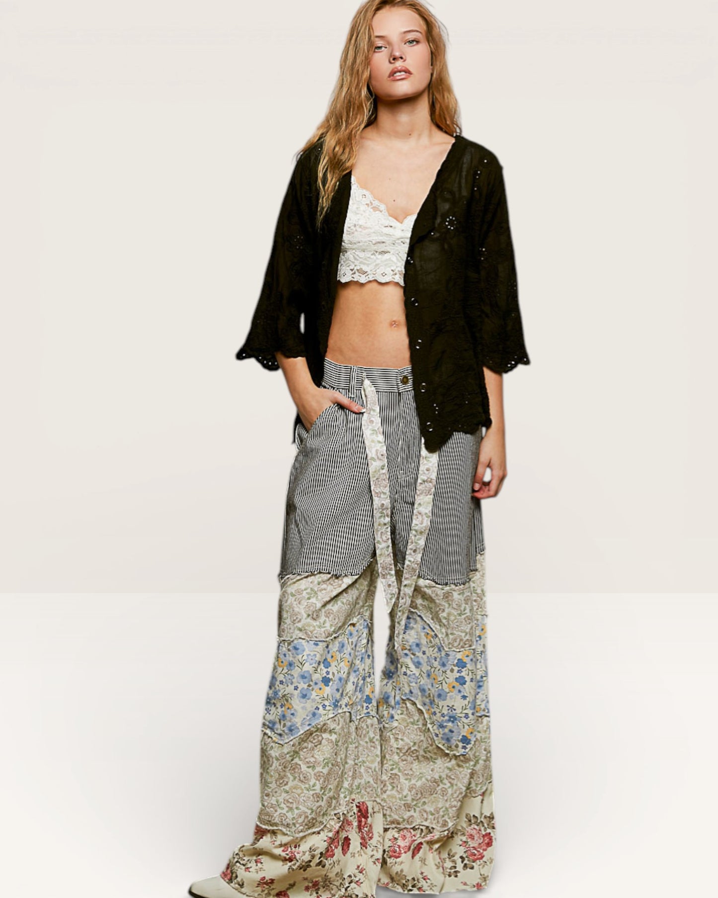 Woman wearing a black cardigan, floral top, and patterned pants on a white background