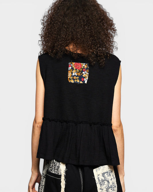 Black sleeveless top with floral pocket on a plain background