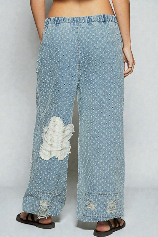 Light blue patterned pants with white distressed patches on a plain background