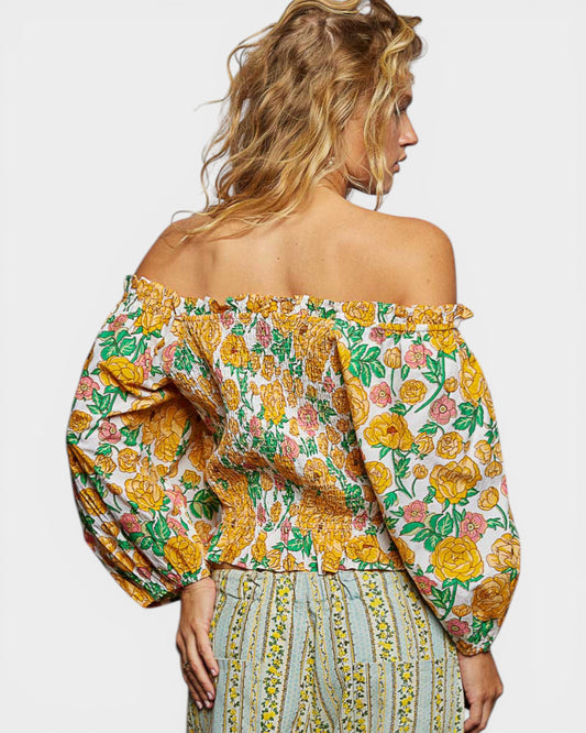 Woman wearing a floral off-shoulder top with puffed sleeves on a plain background