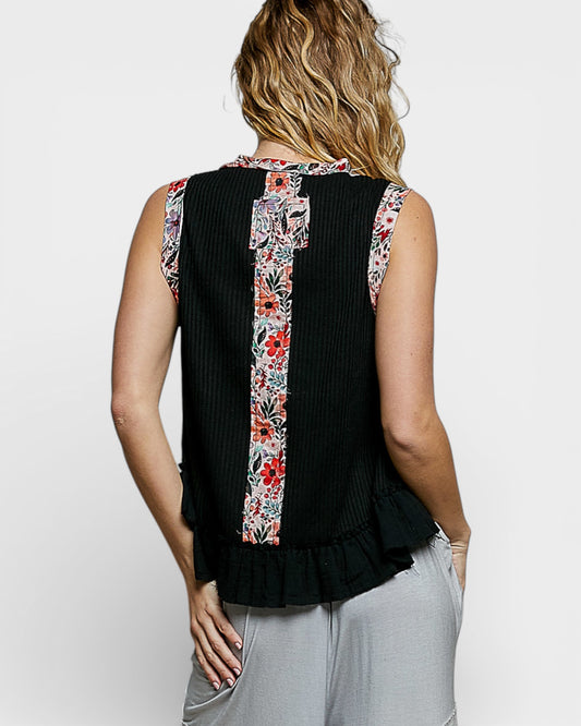 Black sleeveless top with floral trim worn by a person on a white background