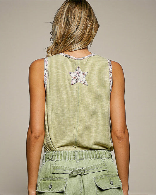 Person wearing a green sleeveless top with a star design and matching green pants on a beige background