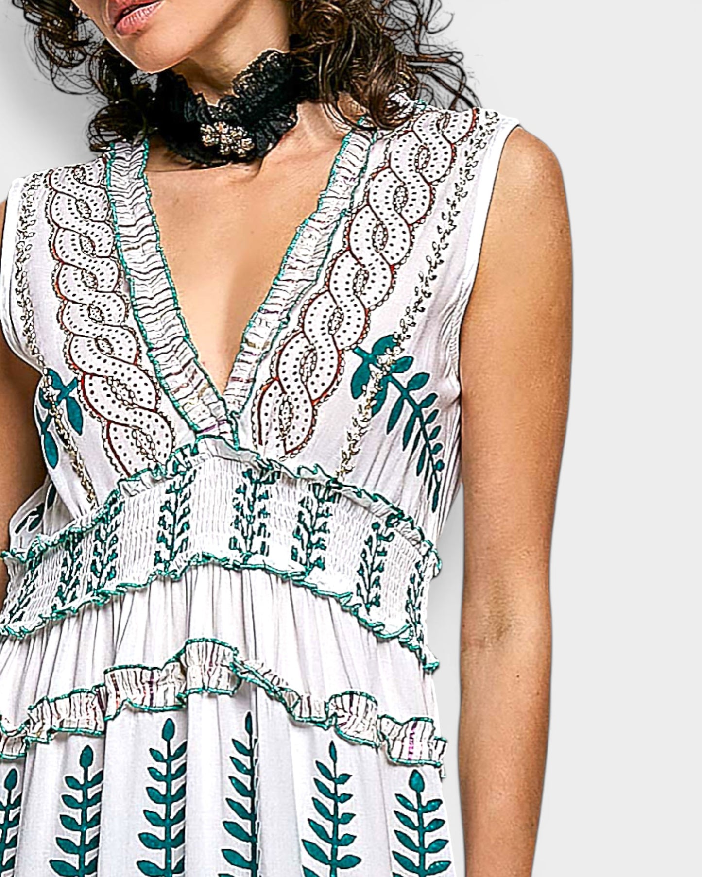 White dress with green leaf patterns worn by a person on a plain background