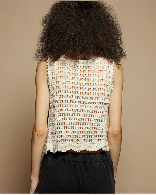 Person wearing a textured sleeveless top against a beige background