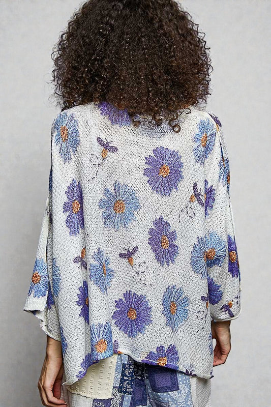 Person wearing a floral patterned cardigan against a plain background