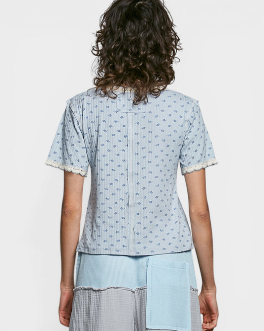 Person wearing a light blue patterned top with matching pants on a white background