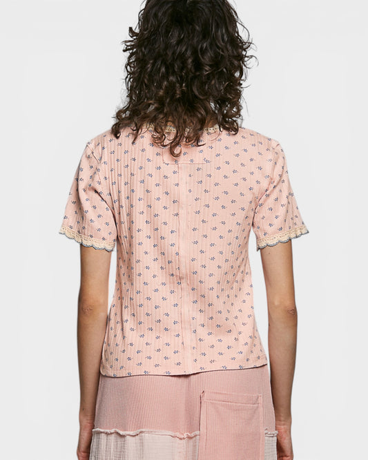 Person wearing a pink patterned top and pants on a white background