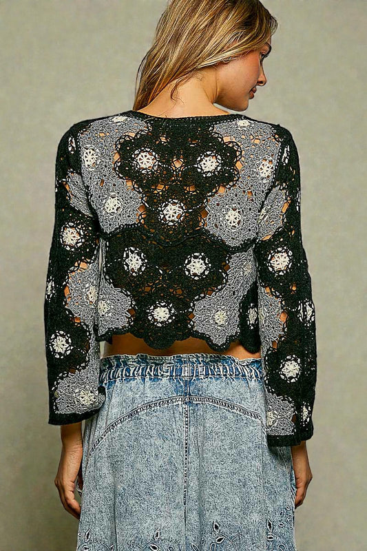 Woman wearing a black and gray crochet top with a plain background