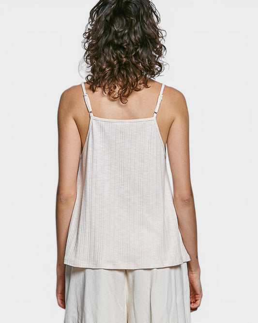 Woman wearing a light-colored sleeveless top and pants on a white background