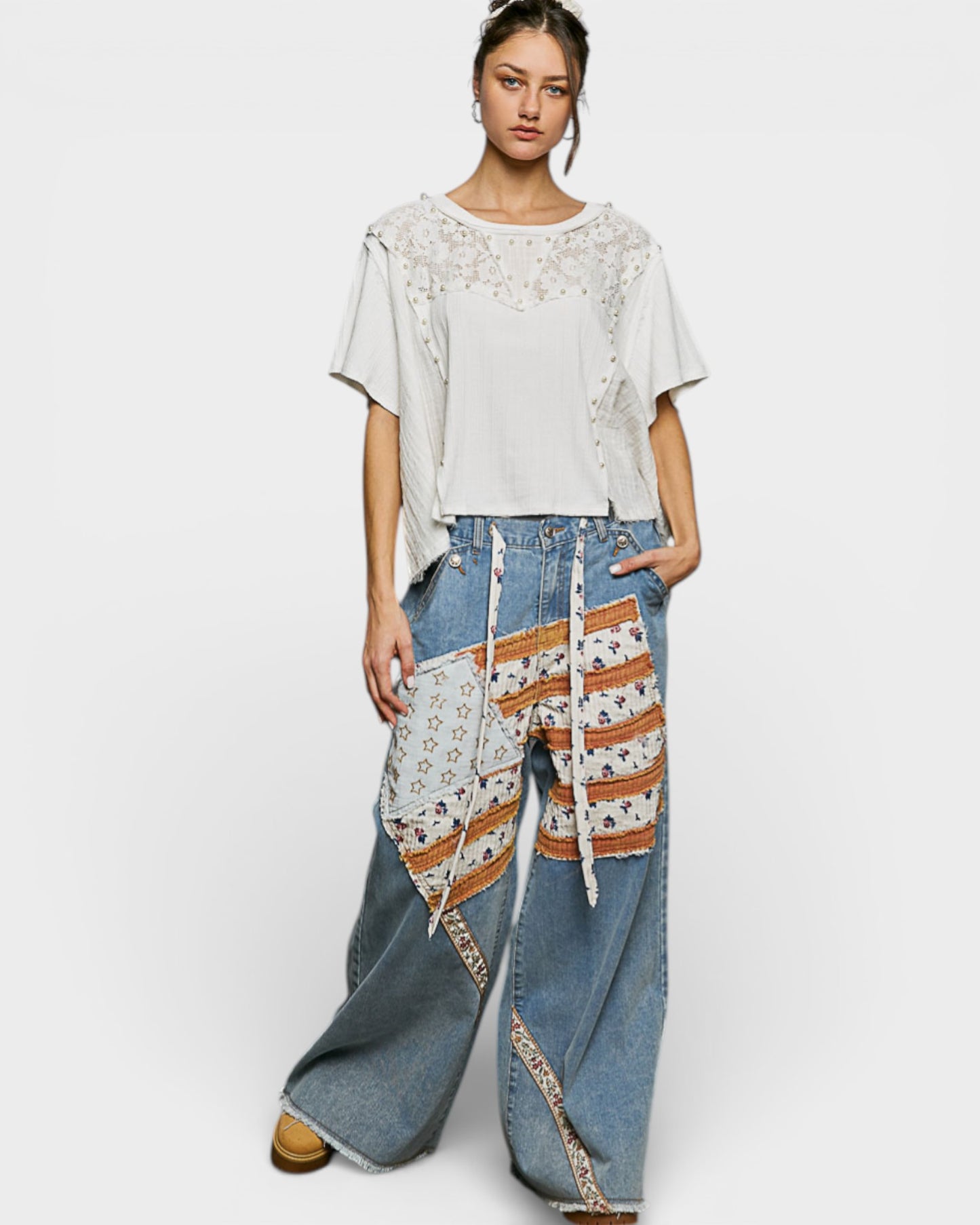 Woman wearing a white top and blue jeans with floral patterns on a white background