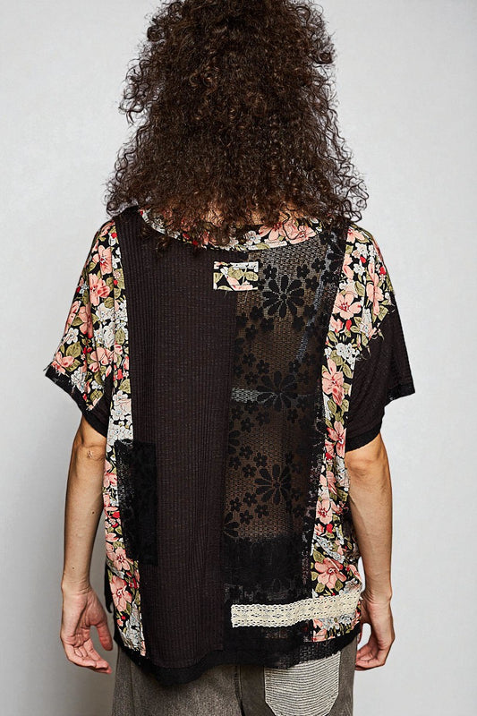 Person wearing a floral kimono over a black top on a plain background