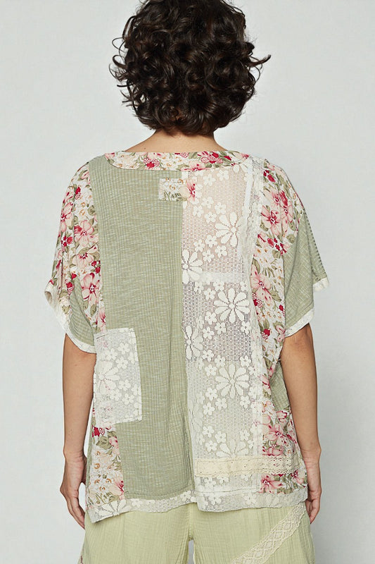Woman wearing a patchwork blouse with floral and lace patterns on a plain background