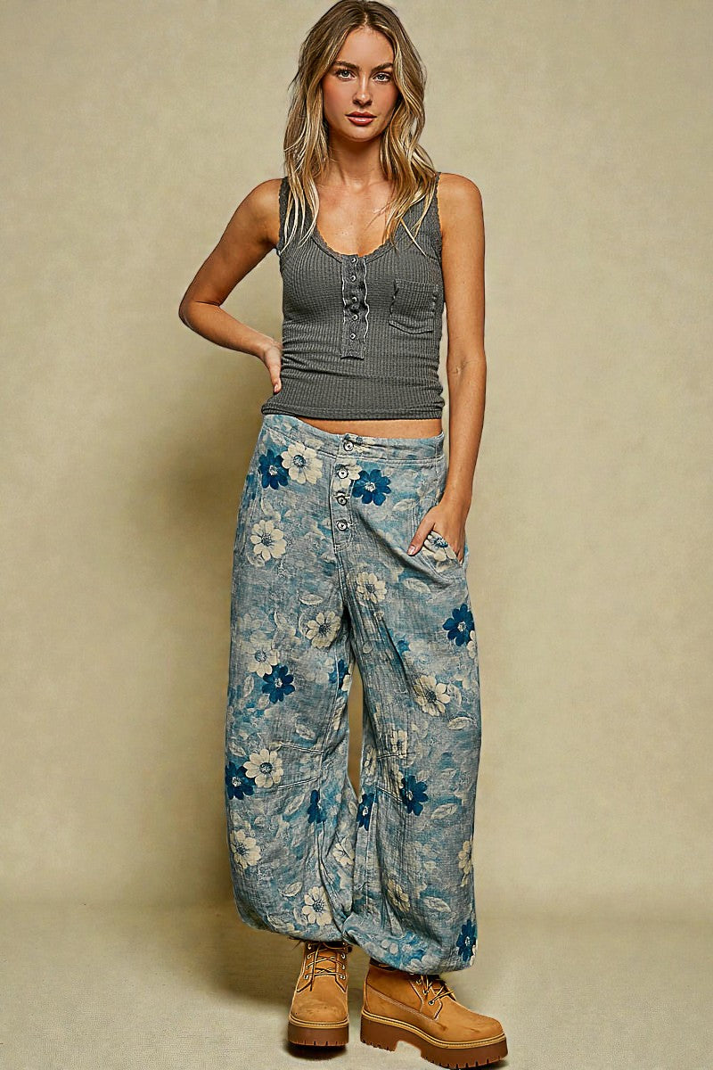 Woman wearing a gray tank top and blue floral pants against a beige background