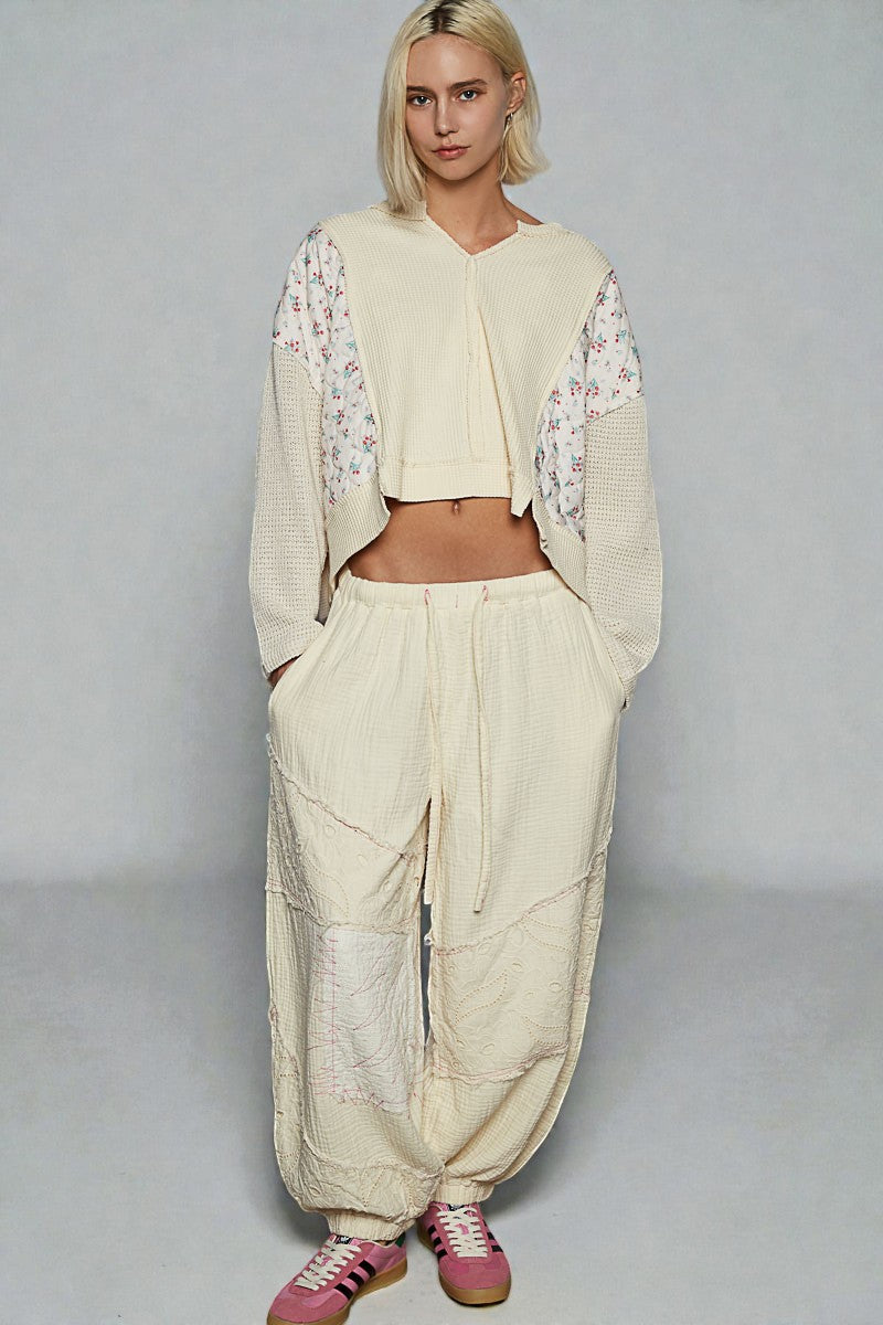 Person wearing a beige outfit with floral sleeves on a plain background