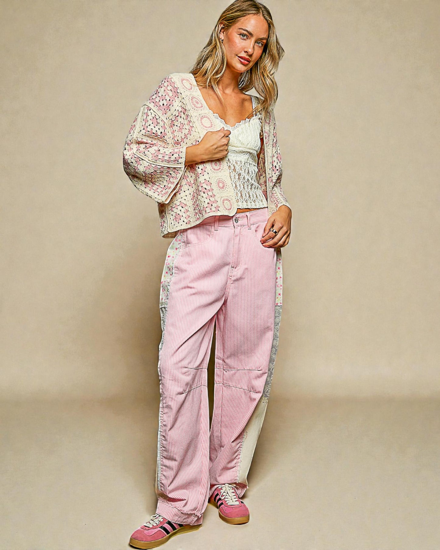 Woman wearing a floral top and pink pants against a beige background