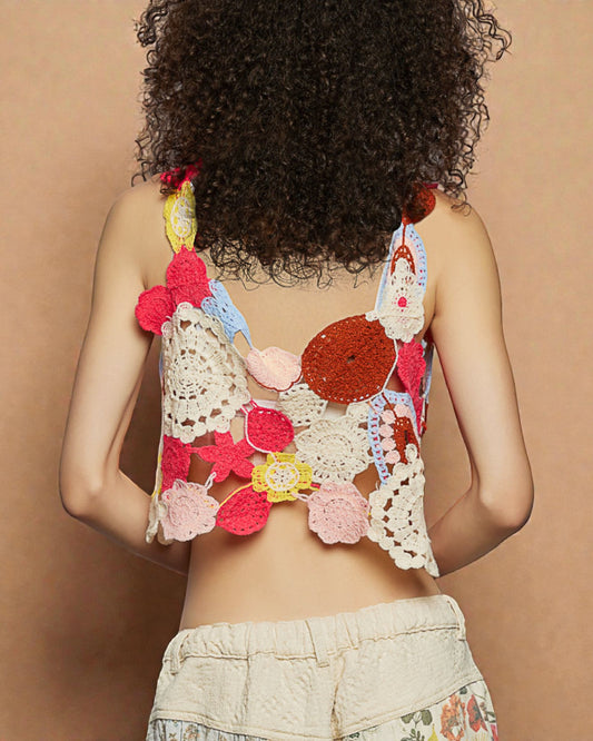 Person wearing a colorful, crochet-style top against a beige background
