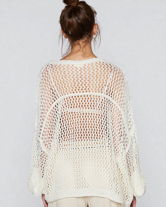 Woman wearing a white crochet top against a plain background