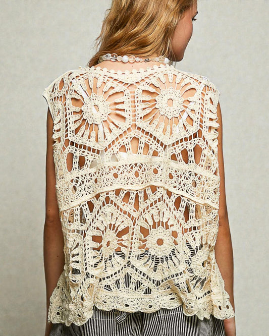 Woman wearing a beige crochet lace top against a neutral background