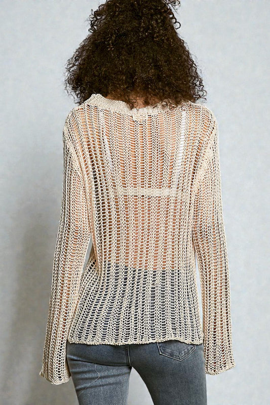 Person wearing a knitted beige sweater against a plain background
