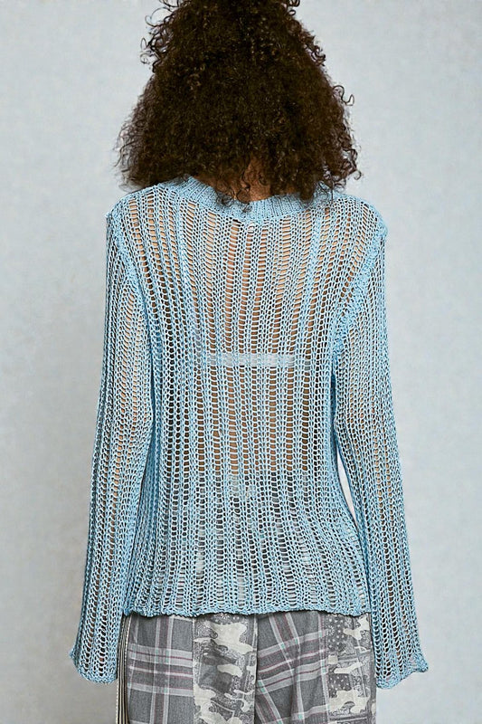 Person wearing a light blue knitted cardigan against a plain background