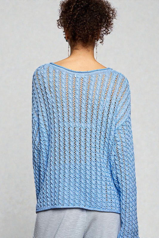 Person wearing a blue knitted sweater on a gray background
