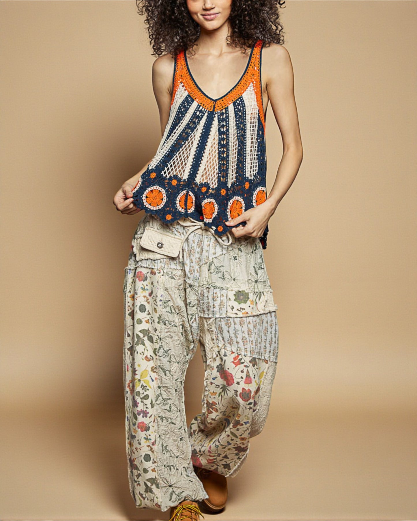 Woman wearing a colorful crochet top and patterned pants on a beige background