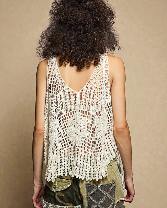 Person wearing a white crochet top against a beige background
