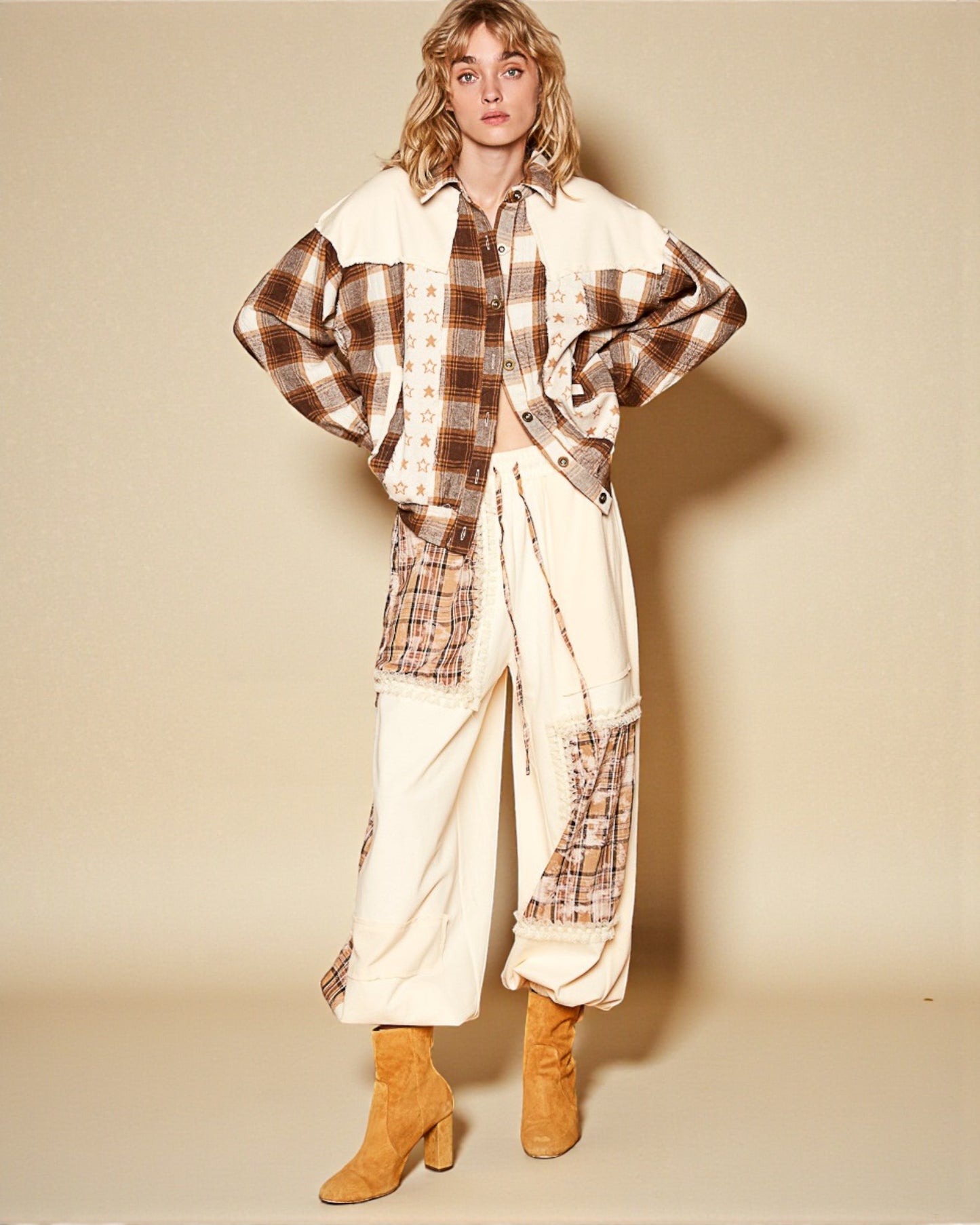 Person wearing a plaid shirt and white pants with brown accents on a beige background