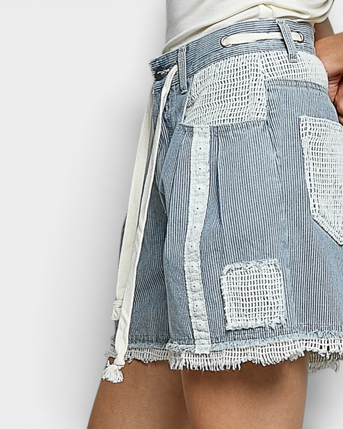 Denim shorts with white lace detailing on a plain background