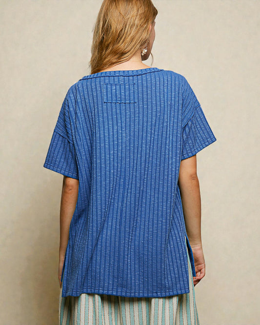 Woman wearing a blue textured top against a beige background