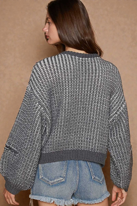 Person wearing a textured sweater and denim shorts against a beige background