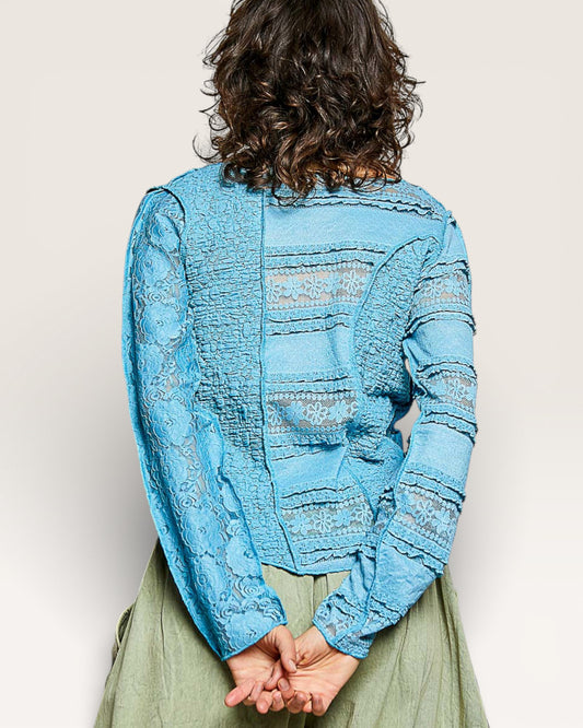 Person wearing a blue textured jacket with a neutral background