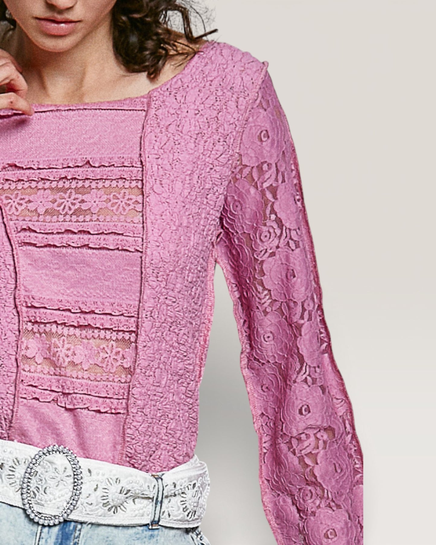 Pink lace top with a white belt on a plain background